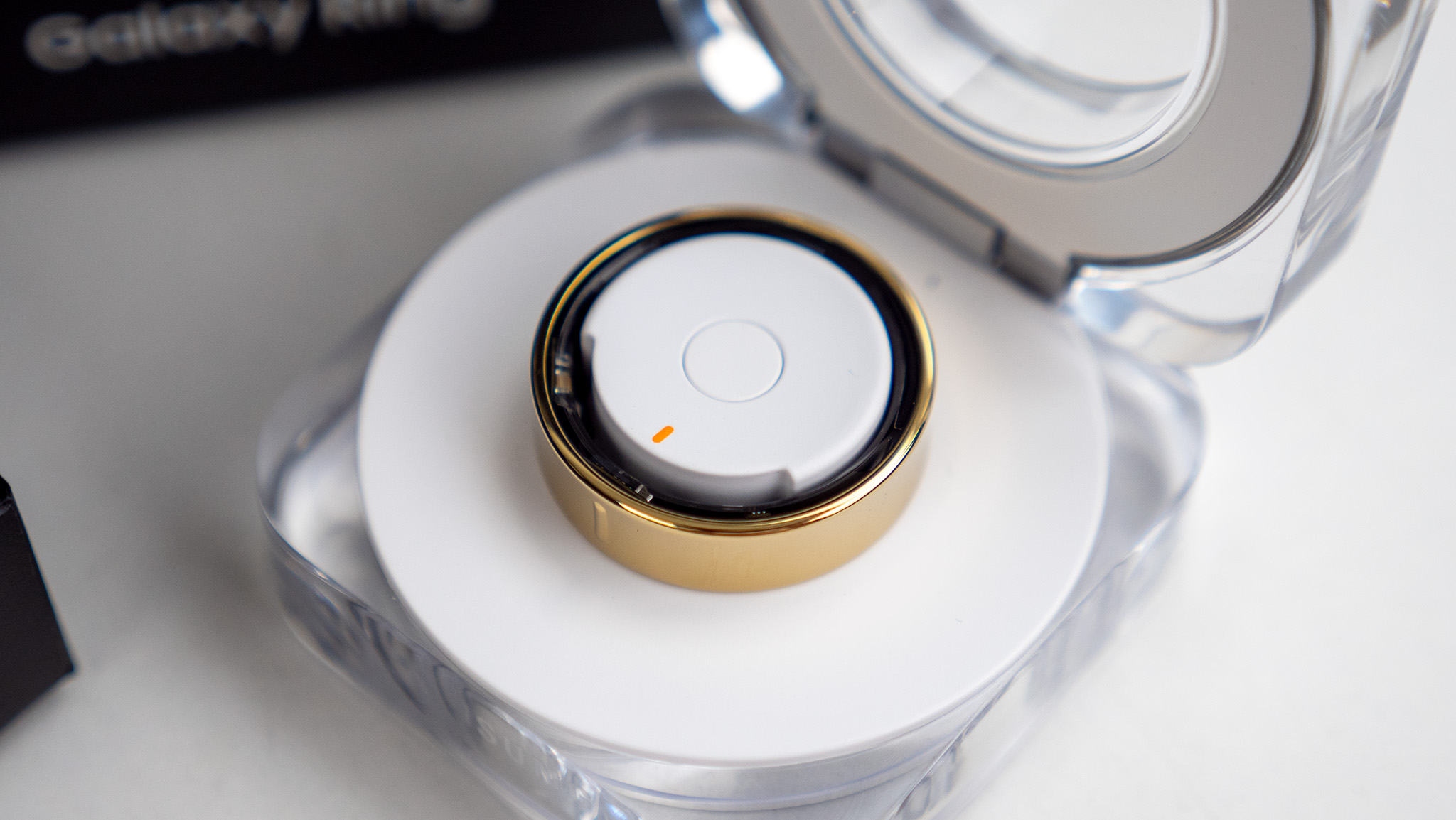 The gold Samsung Galaxy Ring with its box and charging case