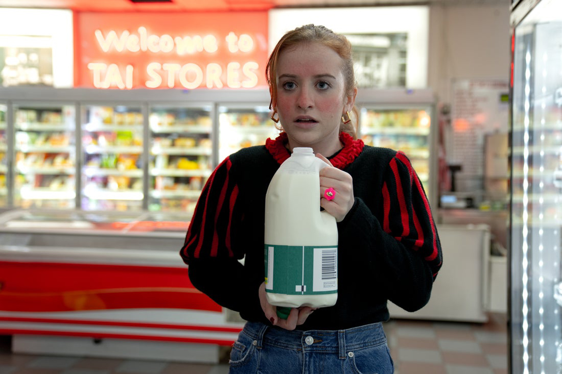 A surprised Jen holds a milk carton in Extraordinary on Disney Plus