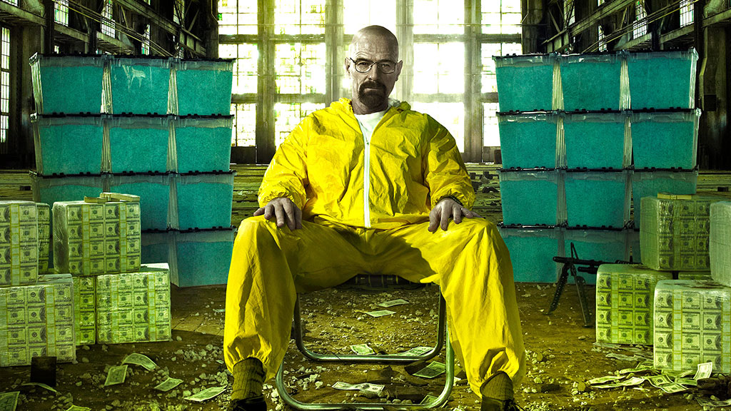 Walter White in a yellow jumpsuit surrounded by money in Breaking Bad.