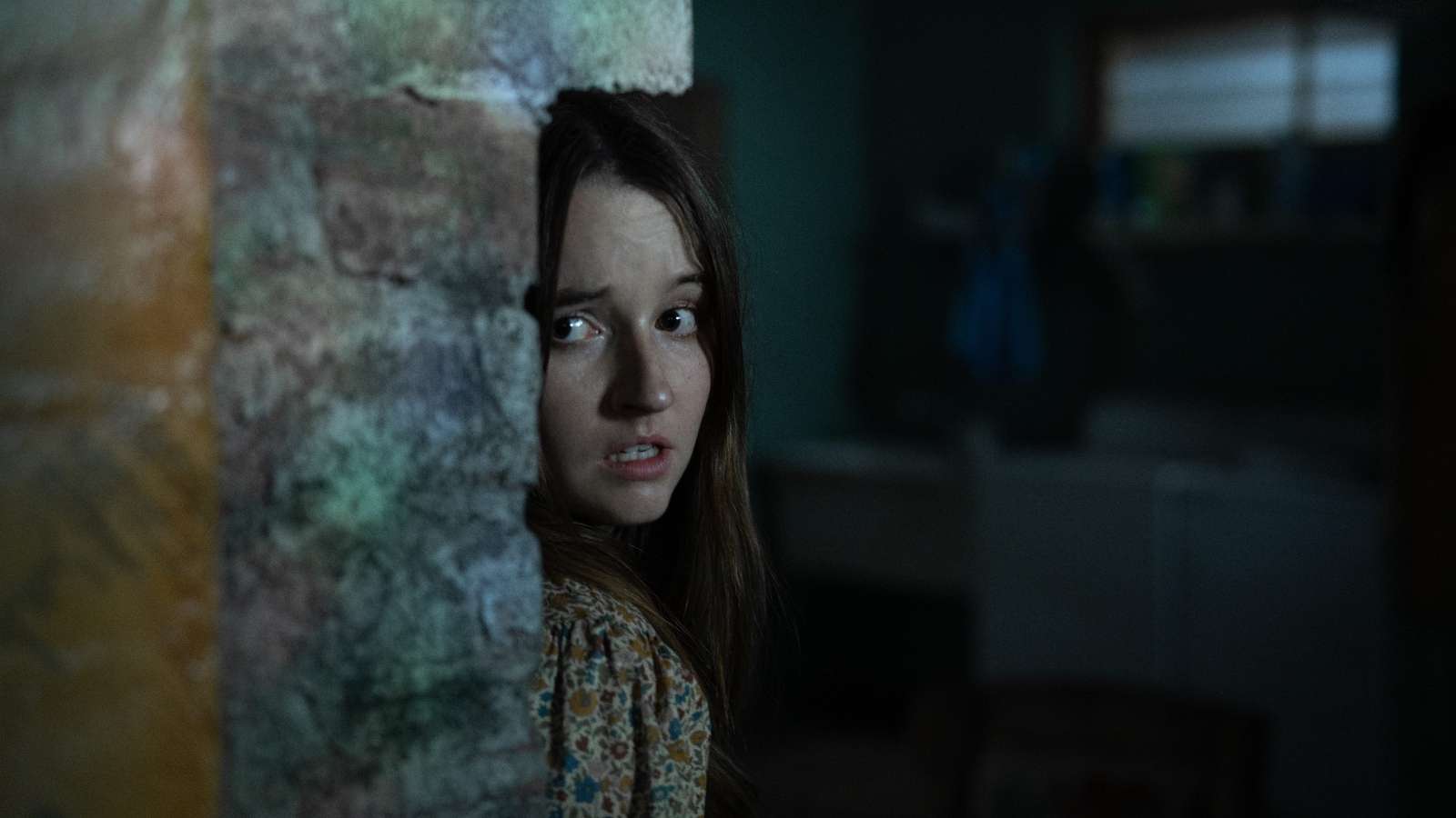 Kaitlyn Dever hiding behind a wall