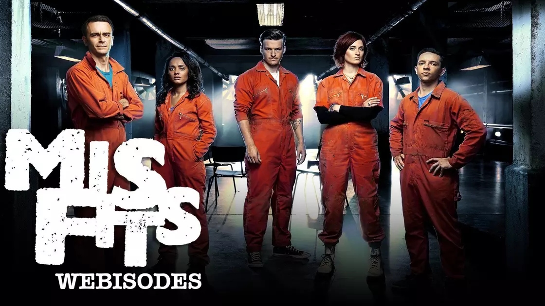 The Misfits cast wearing orange jumpsuits standing in a line and looking at the camera.