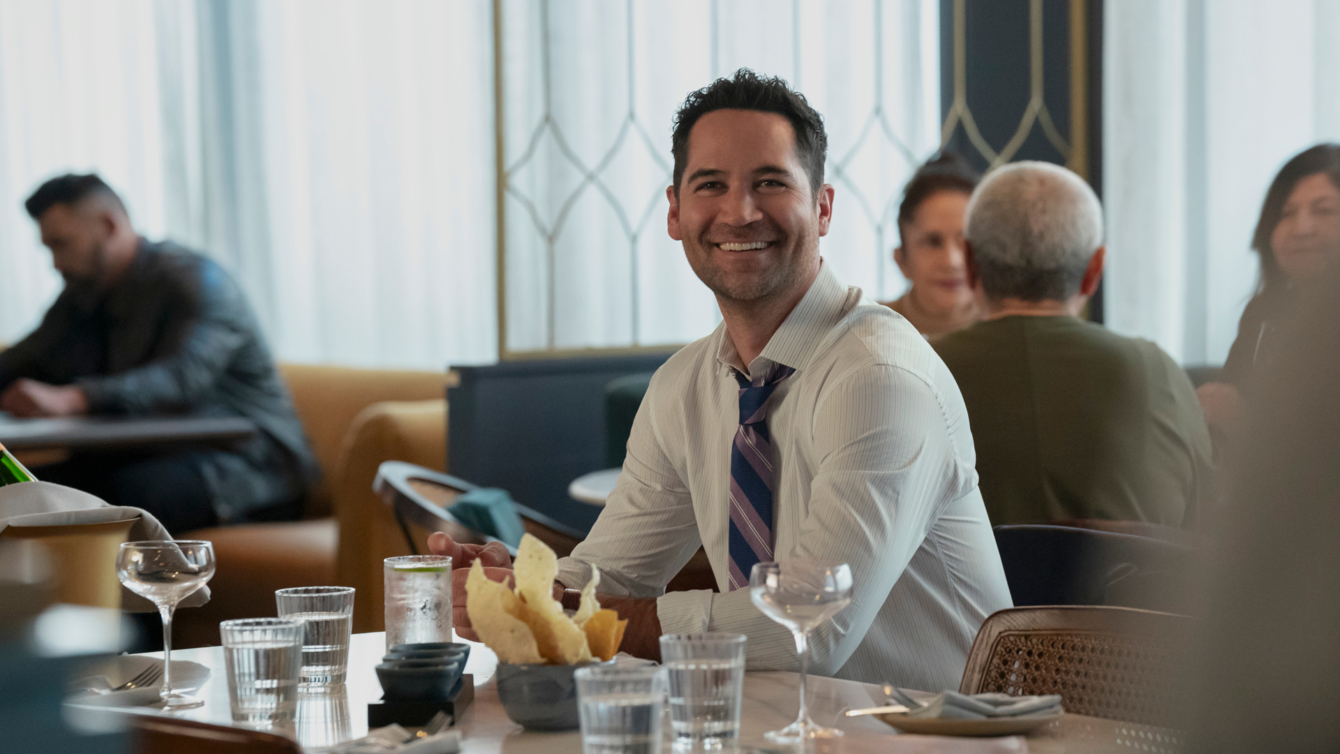 Mickey Haller smiles as he sits at a table in The Lincoln Lawyer season 3