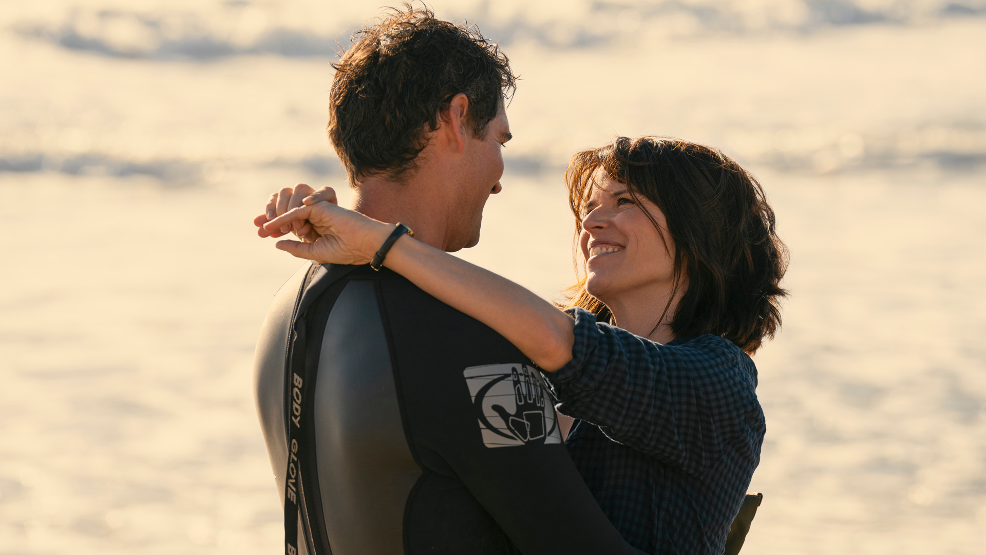 Mickey and Maggie share a romantic moment on a beach in The Lincoln Lawyer season 3