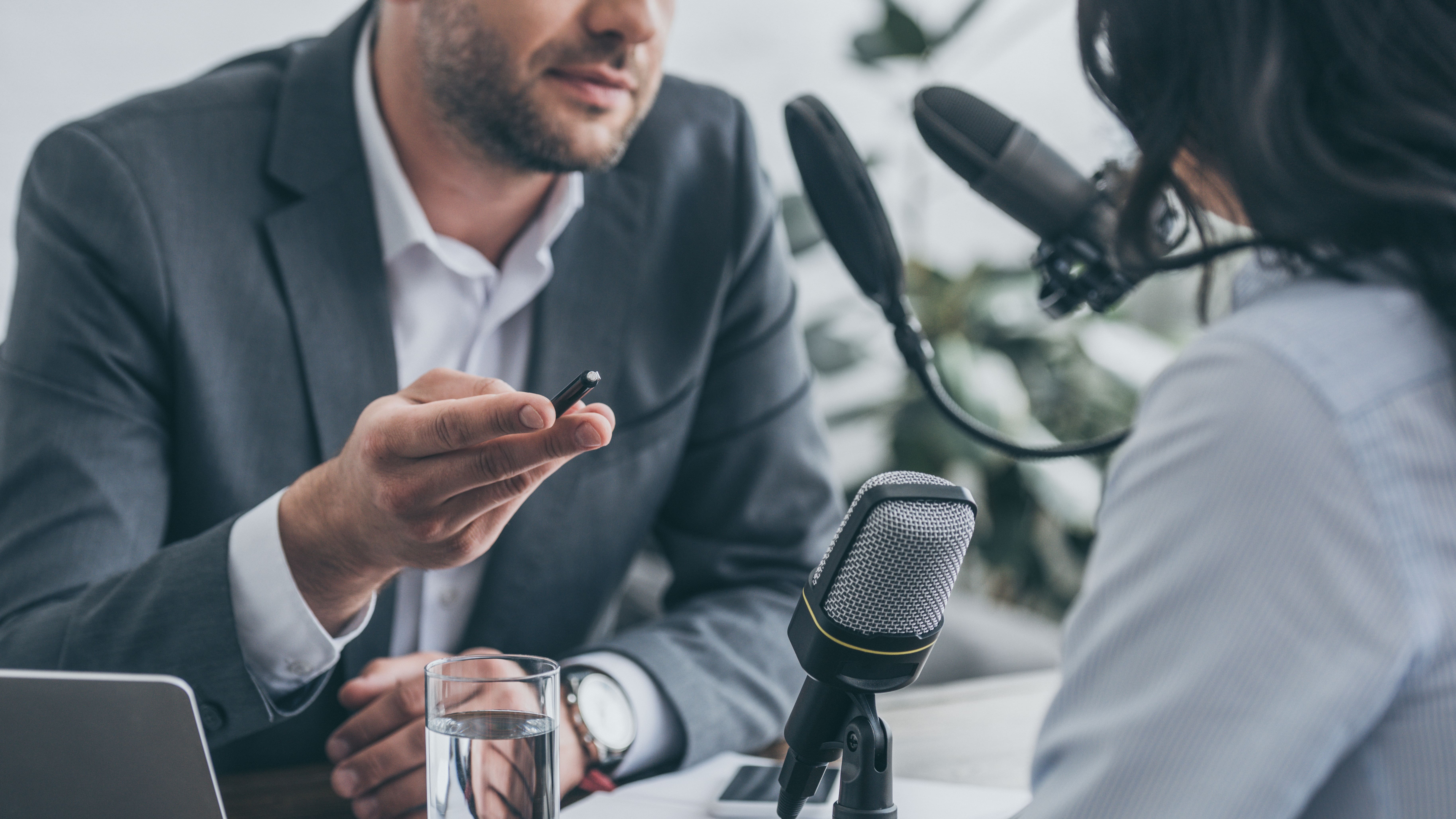 cropped view of radio host gesturing while interviewing businesswoman in broadcasting studio