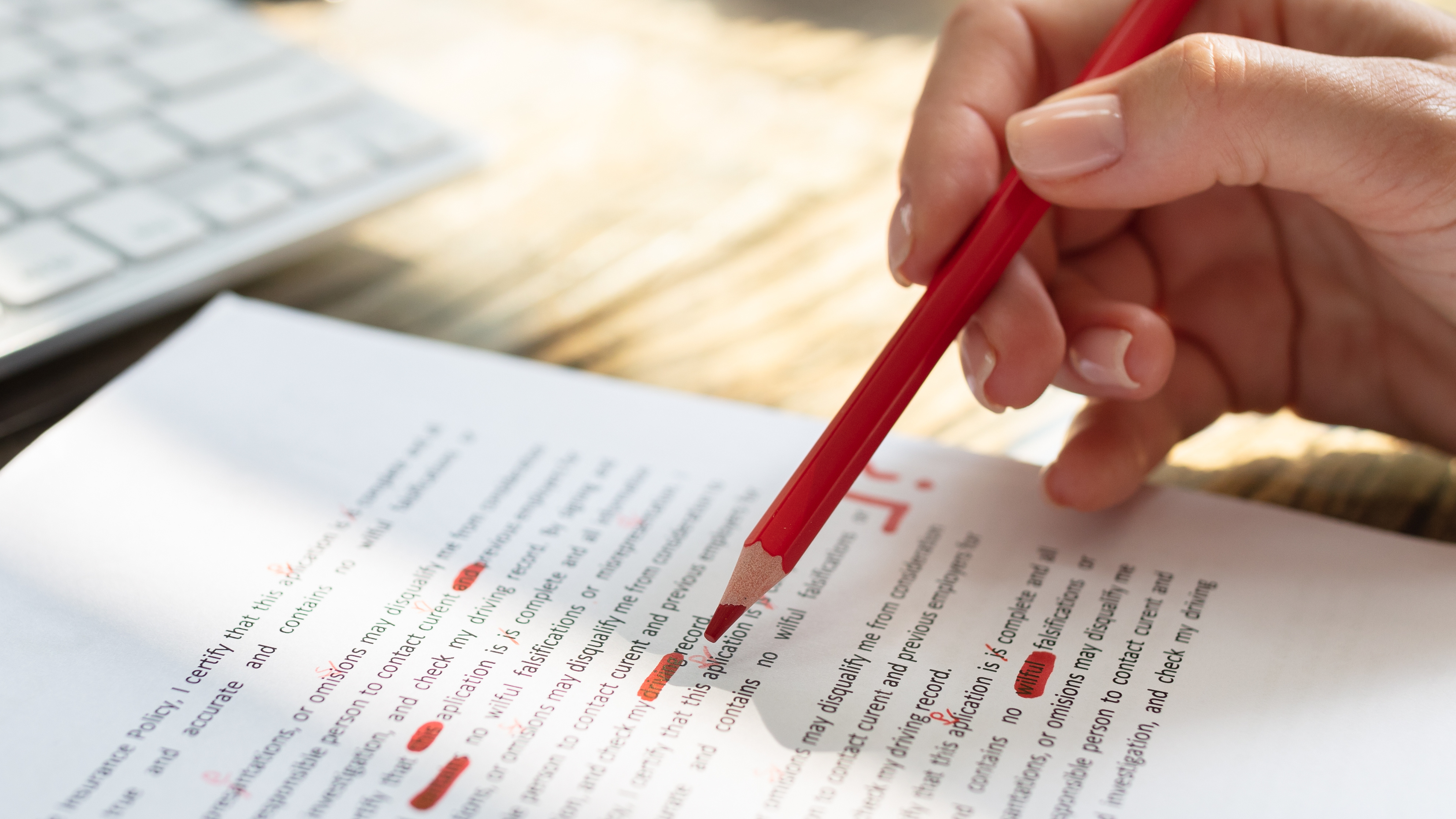 Close-up Of A Person's Hand Marking Error With Red Marker On Document