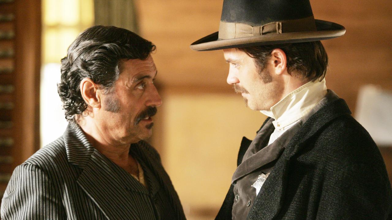 Two male characters look at each other in Deadwood on HBO