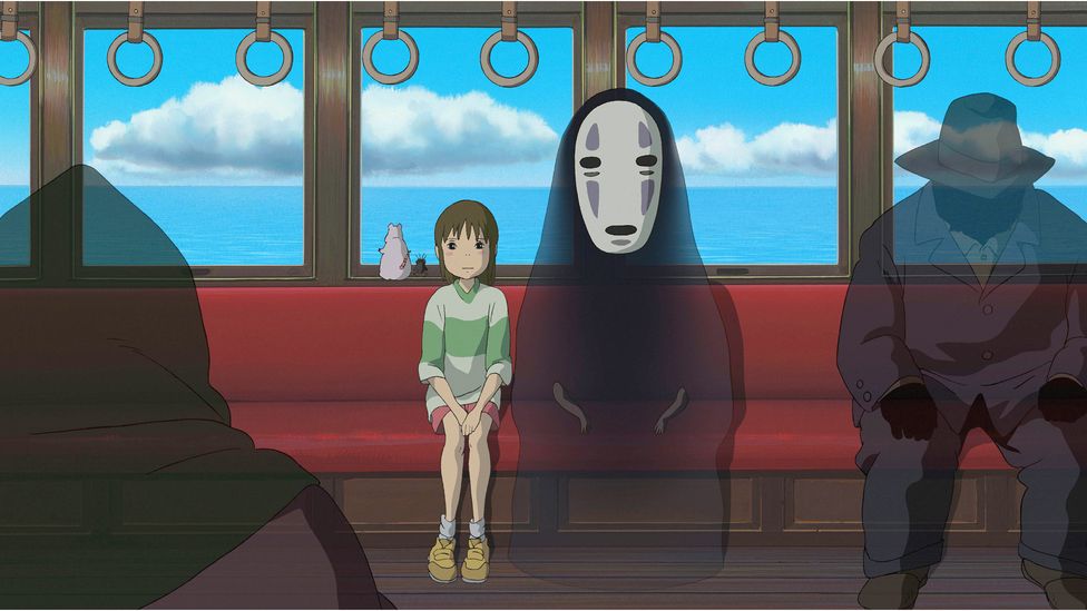 A still from Spirited Away in which Chihiro and a spirit sit on a train