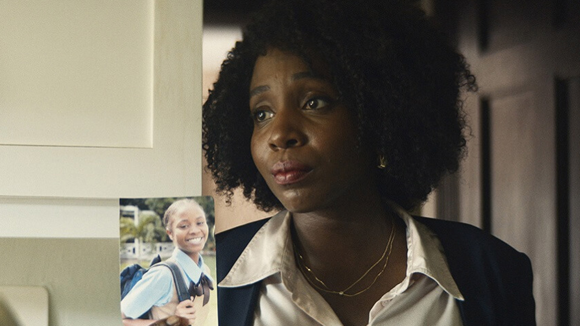 A woman stands next to a cabinet with a child's school photograph pinned to it