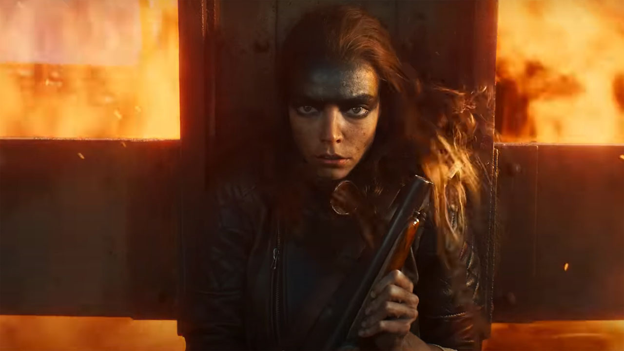 Anya Taylor-Joy's Furiosa holds a shotgun as she shelters from an explosion in Furiosa: A Mad Max Saga