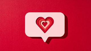 Paper craft image of a multi layered red love heart inside a speech bubble on a red background