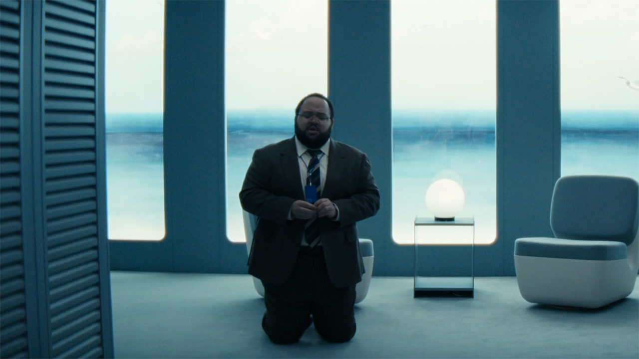 Dylan kneeling on the floor of the Family Visitation Suite in Severance season 2 episode 9