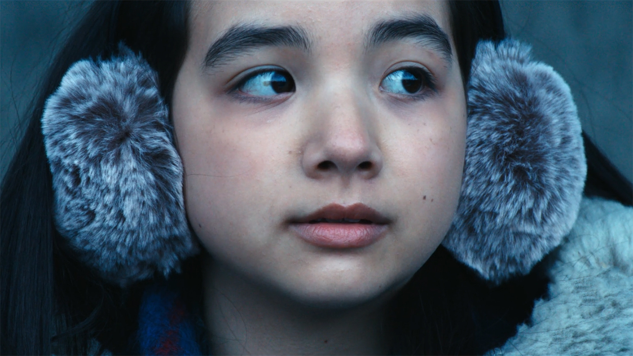 A close up of Sarah Bock's Ms Huang wearing ear muffs in Severance season 2 episode 9