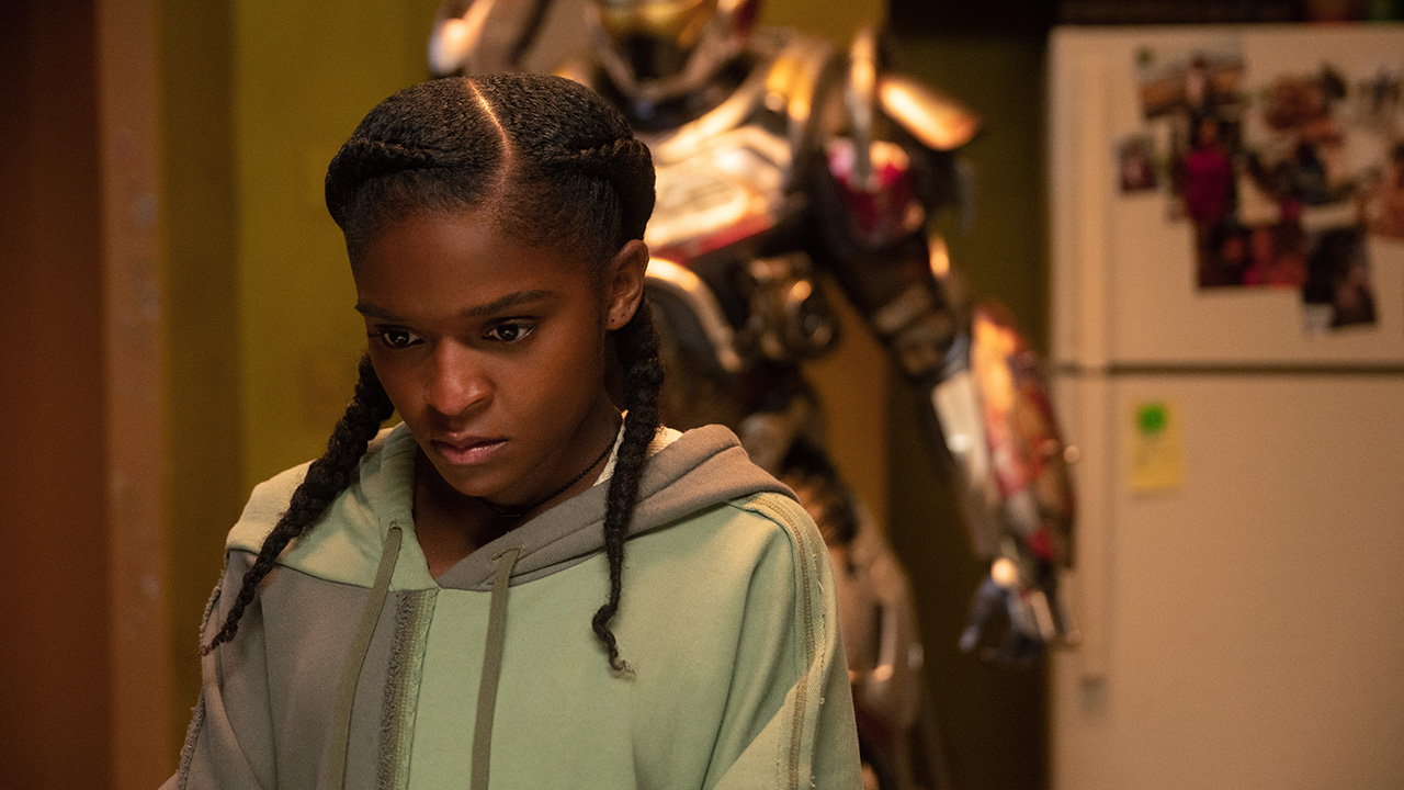 Riri Williams working on something as her super-suit stands in the background in Ironheart